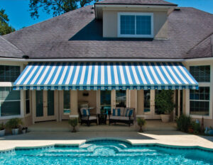 Sunesta awning overlooking a crystal clear pool and providing shade for poolside seating area.