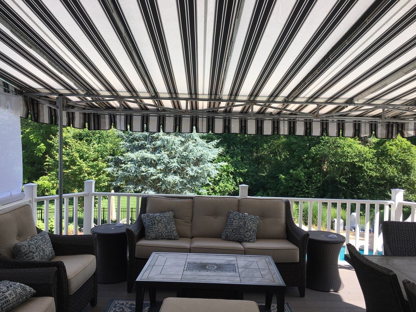 View from underneath a striped stationary awning providing ample shade for a deck seating area.