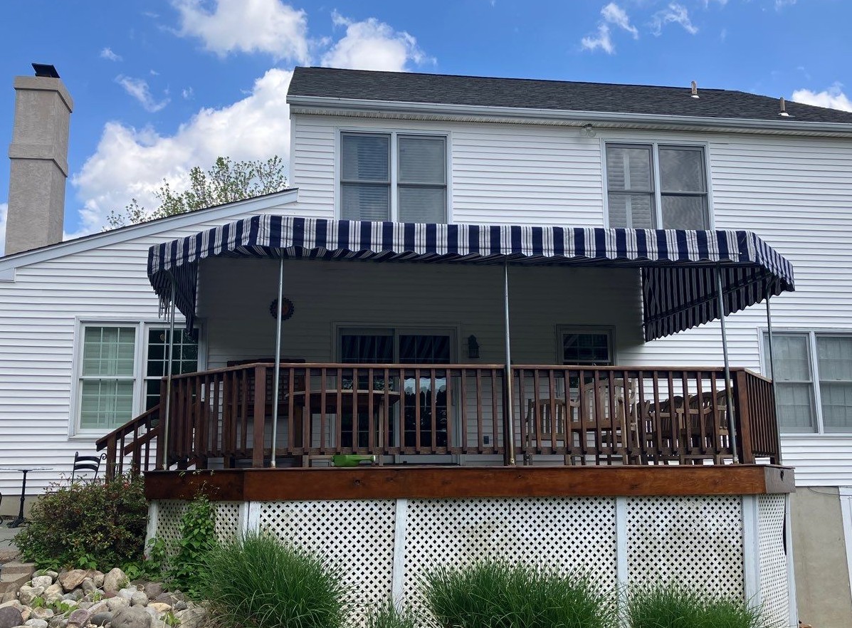 Low ground view of a striped stationary awning providing ample shade for a raised deck seating area.
