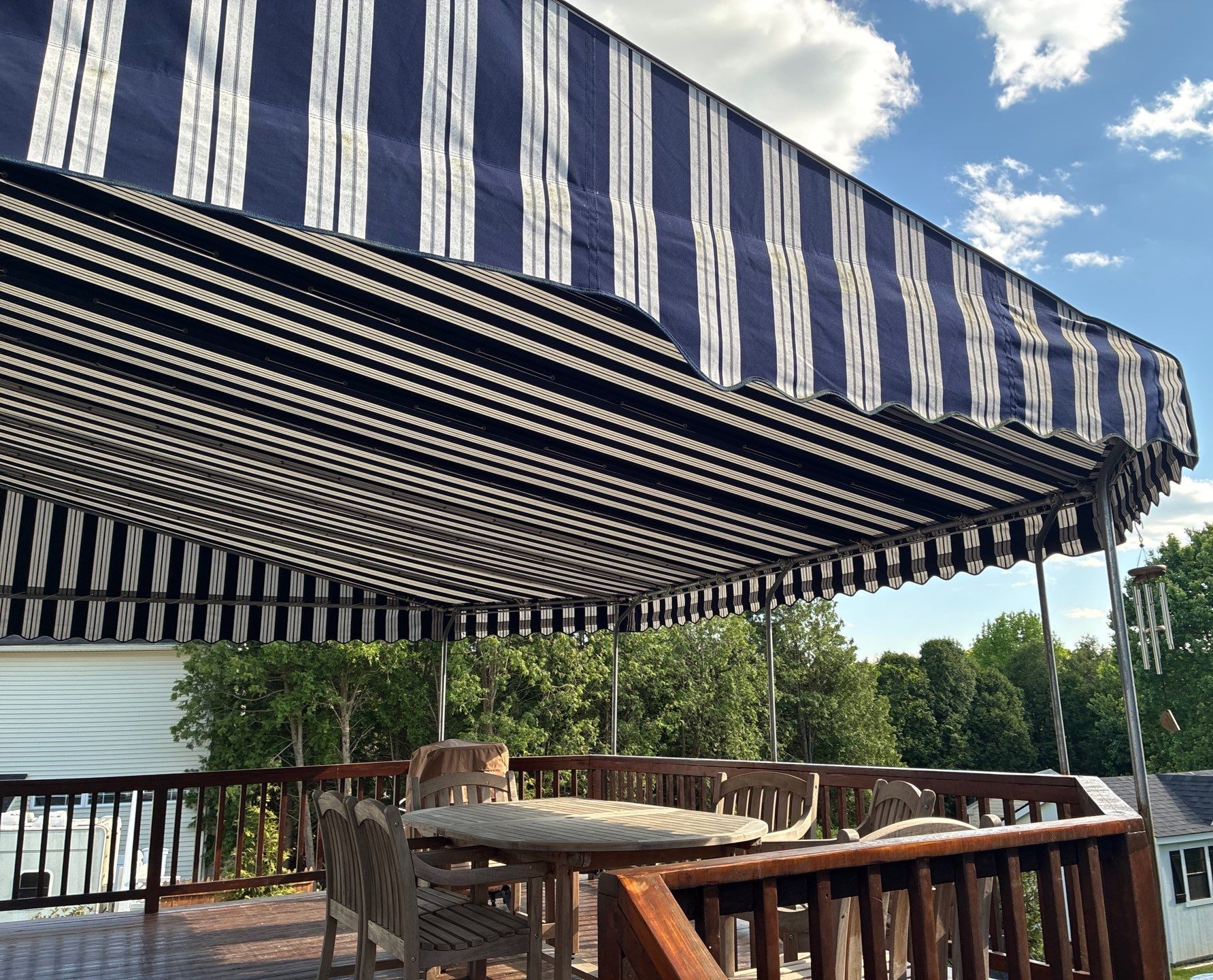 Side view of a striped stationary awning providing ample shade for a deck seating area.